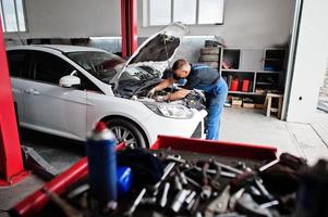 auto reparatie en onderhoud thema. monteur in uniform werken in autoservice, motor controleren. foto