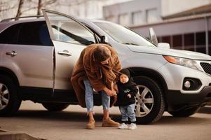 jonge moeder en kind staan in de buurt van hun suv-auto. veiligheid rijden concept. foto