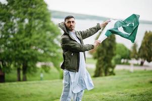 traditionele kleding indisch pakistaans mannelijk portret houdt de vlag van pakistan vast. foto
