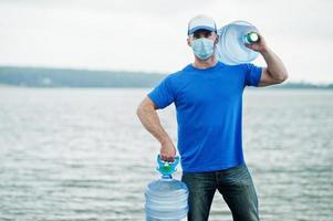 levering water man draagt beschermend gezichtsmasker tijdens coronavirus pandemie. foto