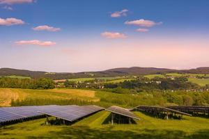 zonnepark met fotovoltaïsche panelen bij zonsondergang foto