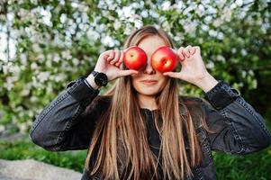 jonge brunette meisje op jeans zittend op plaid tegen lente bloesem boom en appel ogen tonen. foto