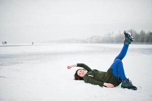 grappige meisjesslijtage op lang groen sweatshirt en jeans, bij bevroren meer in de winterdag. foto