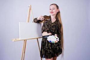 mooie vrouw kunstenaar schilder met borstels en olie canvas poseren in studio geïsoleerd op wit. foto