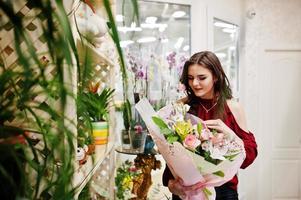 brunette meisje in het rood bloemen kopen bij bloemenwinkel. foto