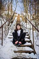 modieuze lange benen brunette model in lange zwarte mantel poseerde buiten op winterdag. foto