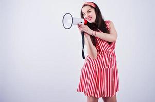 portret van een jonge mooie vrouw in rode jurk praten in megafoon. foto