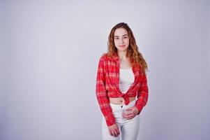jong meisje in rood geruit overhemd en witte broek tegen witte achtergrond op studio. foto