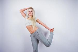 blonde sportieve meisje maakt stretching in de studio tegen een witte achtergrond. foto