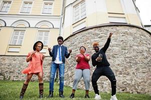 vier Afrikaanse vrienden die plezier hebben en buiten dansen. twee zwarte meisjes met jongens. foto