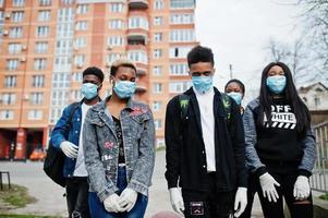 groep afrikaanse tieners vrienden tegen lege straat met gebouw met medische maskers beschermen tegen infecties en ziekten coronavirus virus quarantaine. foto