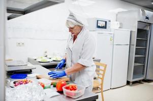 vrouwelijke chef-kok die salade in Italiaanse restaurantkeuken voorbereidt. foto