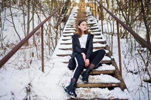 modieuze lange benen brunette model in lange zwarte mantel poseerde buiten op winterdag. foto