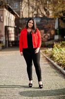 mooie latino model meisje uit ecuador slijtage op zwarte en rode jas gesteld op straat. foto