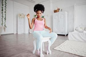 jonge afro-amerikaanse vrouw luistert muziek op oortelefoons in haar kamer. foto