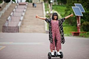 mooie afrikaanse amerikaanse vrouw die segway of hoverboard gebruikt. zwarte meid op zelfbalancerende elektrische scooter met twee wielen. foto