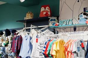 lichte kinderkleding hangt aan het display in de babykledingwinkel. jongens sectie. foto