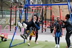 jonge millennials Afrikaanse vrienden op speelplaats, glijbaan en schommel. gelukkige zwarte mensen die samen plezier hebben. generatie z vriendschapsconcept. foto