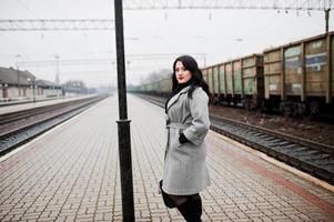 brunette meisje in grijze jas poseerde in treinstation. foto