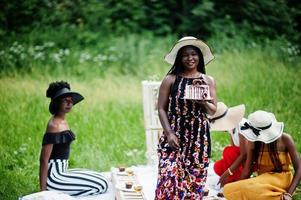 groep afro-amerikaanse meisjes vieren verjaardagsfeestje en houden taart buiten met decor. foto