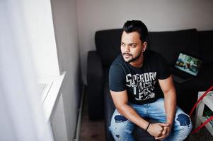 casual baard Indiase man zit op kamer tegen laptop. foto