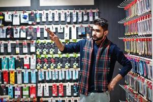 indiase man klant koper bij mobiele telefoon winkel kiest een hoesje voor zijn smartphone. Zuid-Aziatische volkeren en technologieën concept. gsm winkel. foto