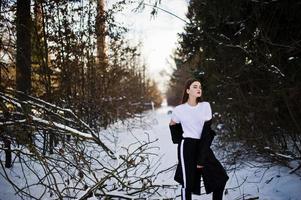 modieuze lange benen brunette model in lange zwarte mantel poseerde buiten op winterdag. foto