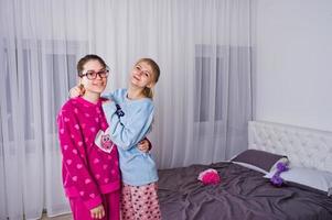 twee vrienden meisjes in pyjama plezier op bed op kamer. foto