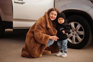 jonge moeder en kind staan in de buurt van hun suv-auto. veiligheid rijden concept. foto