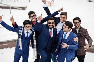 groep van zes Indiase zakenman in pakken poseerde buiten in de winterdag in Europa, knuffels en gelukkige emoties. foto