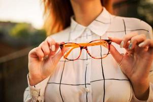 close-up foto van bril met roodharige vrouw, witte blouse dragen.