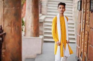 Indiase stijlvolle man in gele traditionele kleding met witte sjaal buiten geposeerd. foto