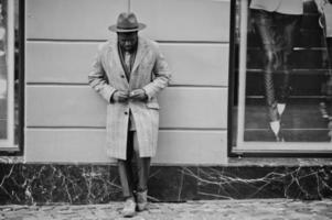 stijlvolle Afro-Amerikaanse man model in grijze jas, jas stropdas en rode hoed. zwart-wit foto. foto