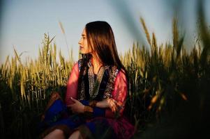 teder indisch meisje in saree, met paarse lippen make-up geposeerd op het veld bij zonsondergang. modieus Indiaas model. foto