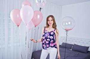 gelukkig meisje met gekleurde ballonnen op bed op kamer. verjaardag thema vieren. foto