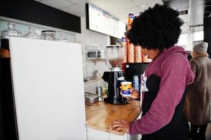 krullend haar Afro-Amerikaanse vrouw draagt een trui in café binnen met een kopje thee of koffie. foto