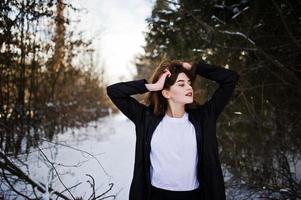 modieuze lange benen brunette model in lange zwarte mantel poseerde buiten op winterdag. foto