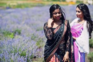 twee mooie indiase meisjes dragen saree india traditionele kleding in paars lavendelveld. foto