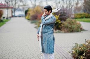 indiase man draagt traditionele kleding met witte sjaal buiten geposeerd. foto