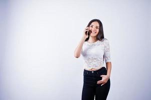 portret van een jonge mooie vrouw in witte top en zwarte broek met behulp van haar telefoon. foto