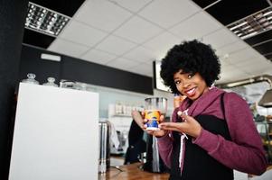 krullend haar Afro-Amerikaanse vrouw draagt een trui in café binnen met een kopje thee of koffie. foto