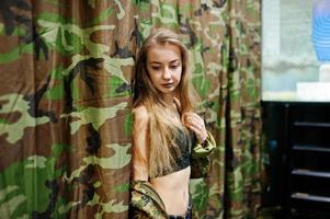 militair meisje in camouflage uniform tegen leger achtergrond. foto