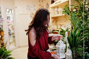 brunette meisje in het rood bloemen kopen bij bloemenwinkel. foto