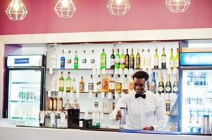 Afro-Amerikaanse barman bij bar met shaker. bereiding van alcoholische dranken. foto