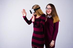 twee meisjes in paarse jurken die een virtual reality-bril uitproberen in de studio. foto