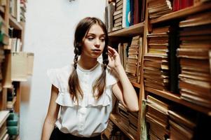 meisje met staartjes in witte blouse bij oude bibliotheek. foto