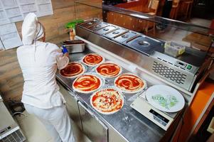 vrouwelijke chef-kok die pizza in restaurantkeuken voorbereidt. foto