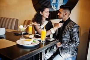 mooi indisch verliefd stel, draag bij saree en elegant pak, geposeerd op restaurant. vrouw gebonden stropdas op haar man. foto