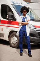 Afro-Amerikaanse vrouwelijke paramedicus staat voor ambulance auto. foto