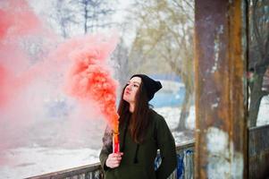 jong meisje met rood gekleurde rookbom in de hand. foto